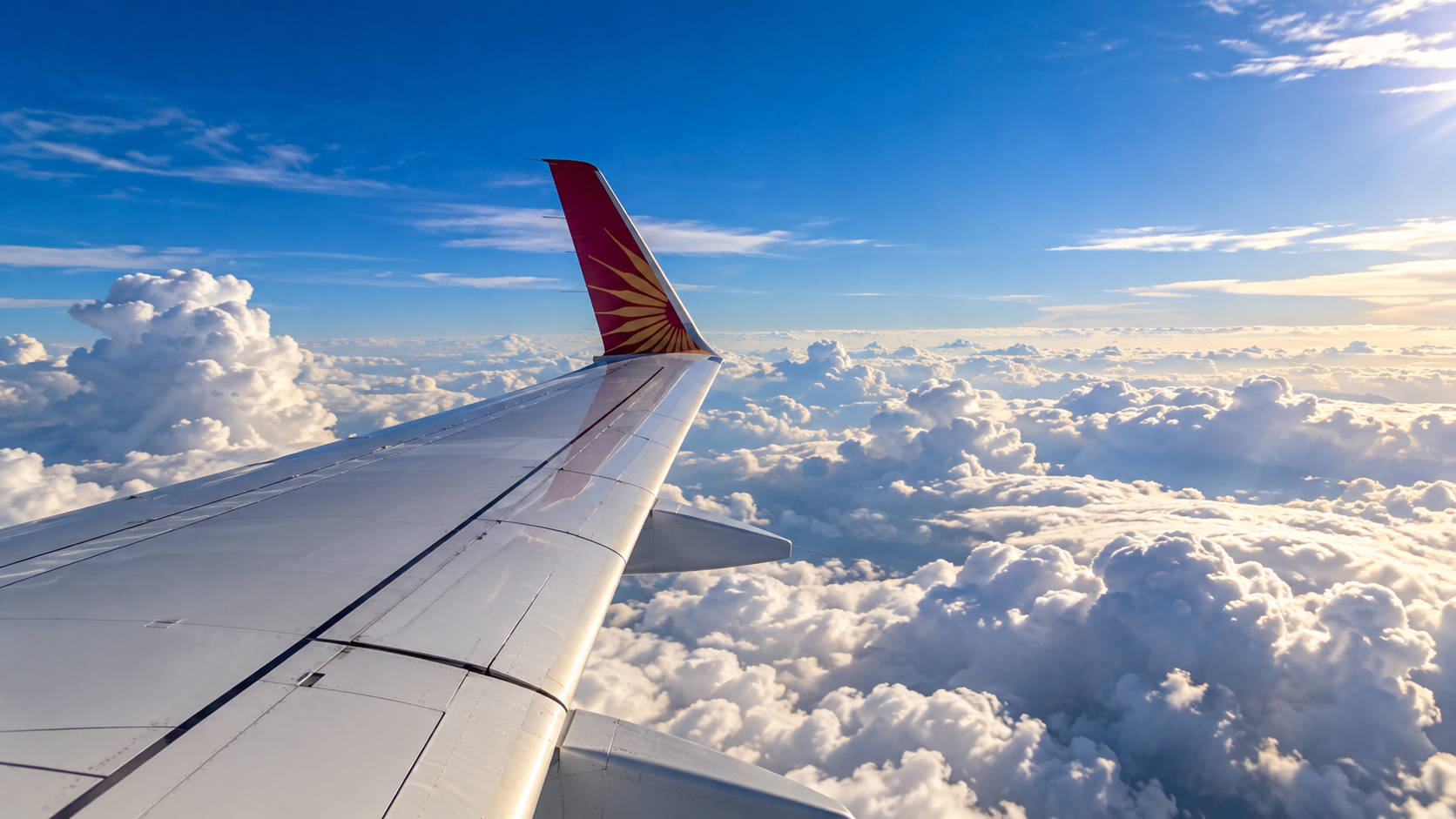 エア・インディアの翼と尾翼越しに広がる雲海と青空