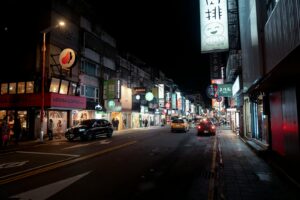 Bustling night street in Taipei with bright city lights and urban activity.