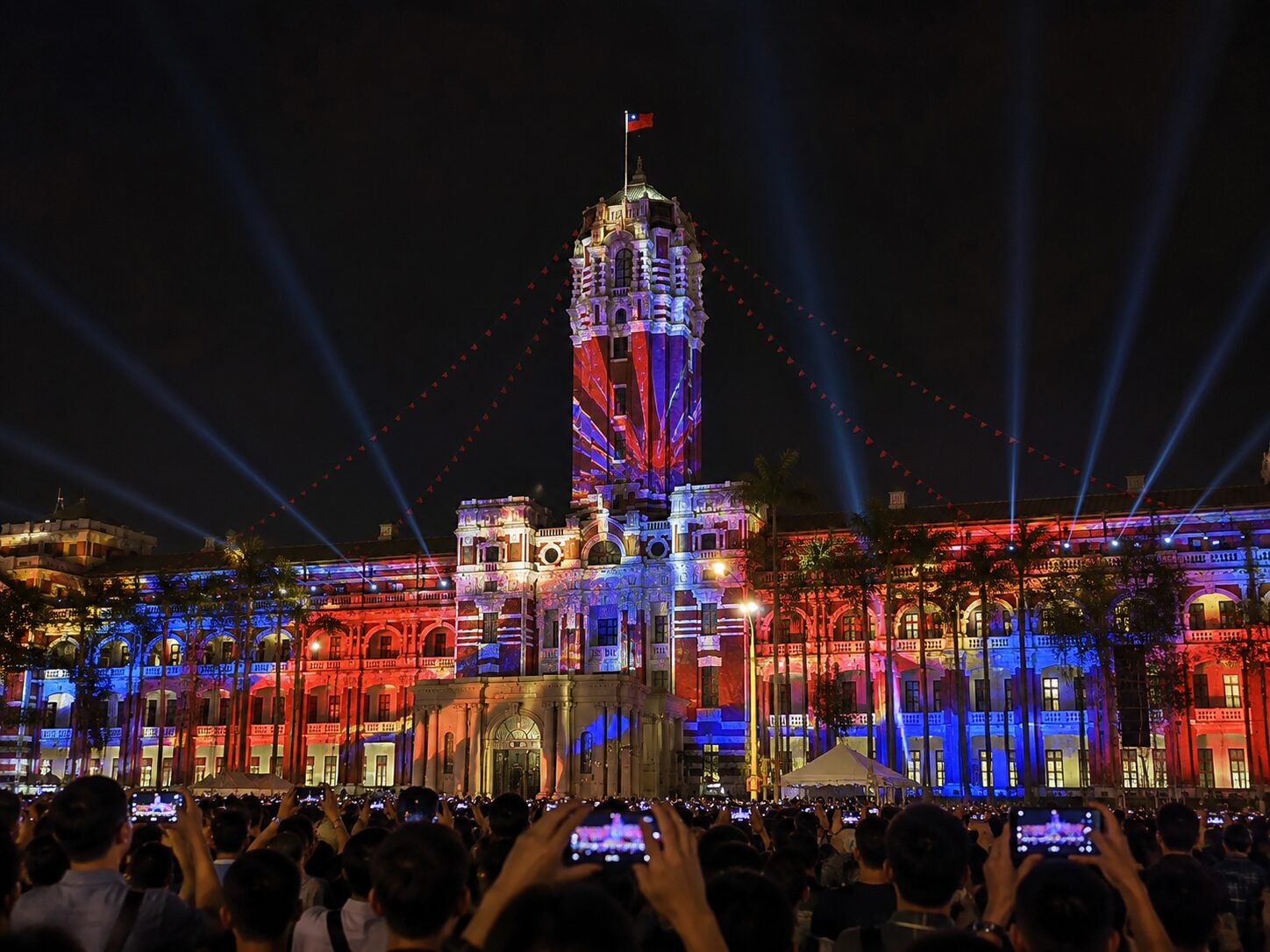 光に包まれた総統府で多くの人々が祝祭の夜を見守る